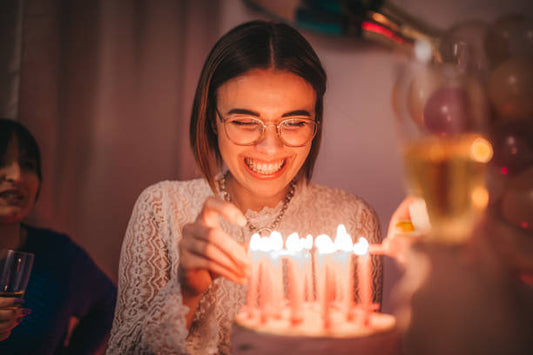 Woman lighting candles on a birthday cake during an evening celebration, ideal for birthday cake Melbourne delivery moments