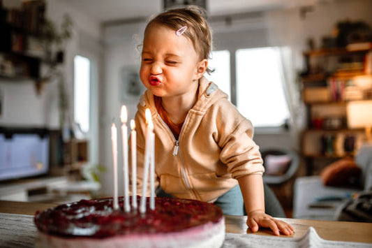 Young child blowing out candles on a birthday cake at home