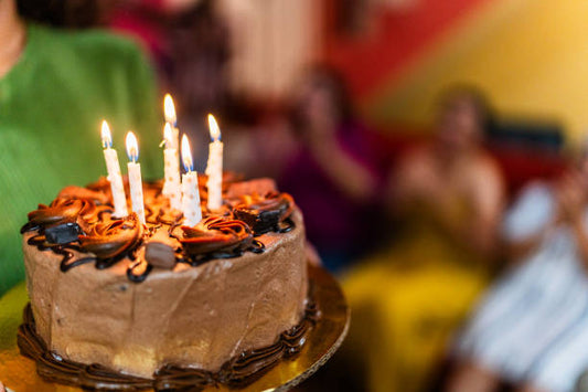 Chocolate birthday cake melbourne with candles lit at family party from local cake shop melbourne